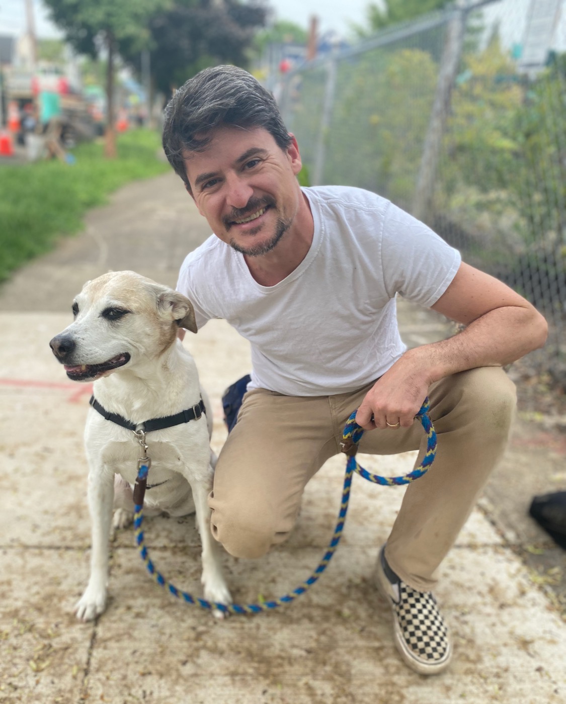 Dusan kneeling beside a cream-colored dog